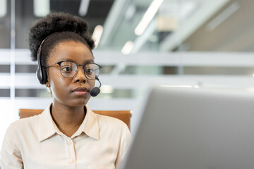 Woman with headset using laptop in bright office. Professional concentrating on tasks, showcasing...