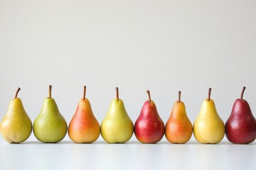 Pears arranged in a line with varying sizes and colors on a neutral background