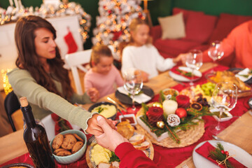 Family holding hands praying before Christmas dinner at home