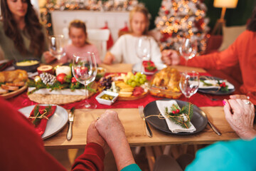 Detail of family praying before Christmas dinner at home