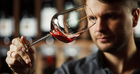 Bokal of red wine on background, male sommelier appreciating drink