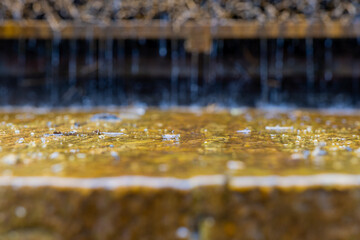 Water droplets fall from a shelf onto a smooth, golden surface