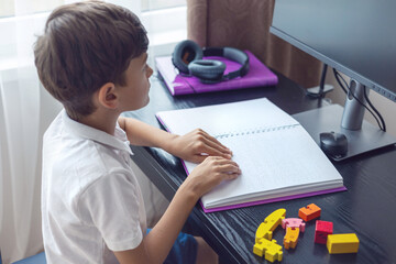 Children's hands on a Braille book – inclusion, blindness, disability. Blind little boy reading...
