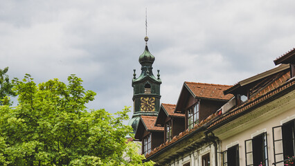 A quaint view of a historic European town with a tall clock tower rising above red-roofed...