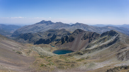Mountain panorama with a little lake in the valley under a bright blue sky