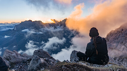 Young woman sitting on the top of the mountains watching a beautiful sunset