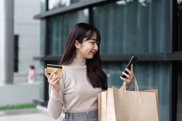 Excited Shopper Holding Credit Card and Smartphone on Black Friday Outside Modern Shopping Mall