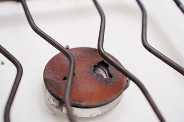 An old broken rusted burner of a gas stove. 