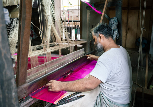 Man using handloom to create a piece of purple clothe