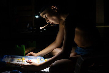 Blackout in Ukraine. Teenager playing pinball with a headlamp
