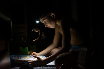 Blackout in Ukraine. Teenager playing pinball with a headlamp