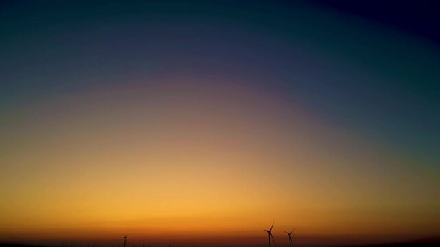 Stunning sunset over wind turbines in a serene landscape at dusk