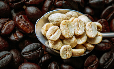 Top view green coffee bean on a stainless steel spoon on roasted coffee bean  background, Close-up, Close-up of unroasted coffee bean