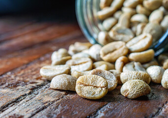 Green coffee beans poured out of a glass jar, Close-up of green raw coffee bean, unroasted coffee bean