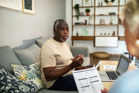 Diverse senior couple reading bills on the couch at home