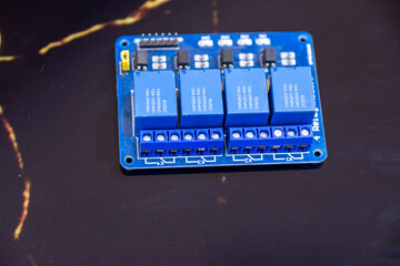 Detailed view of a blue circuit board featuring multiple relay switches. Ideal for electronics, technology, and engineering concepts. Suitable for educational and industrial purposes