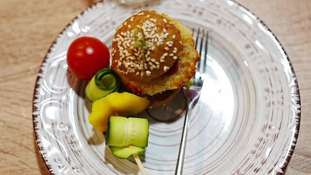 A plate with a mini burger and canapes for a buffet. 