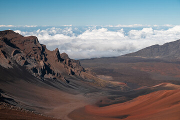 View of the volcano craters at Haleakala with spectacular clouds, blue sky and red dirt (Maui, Hawaii, USA)