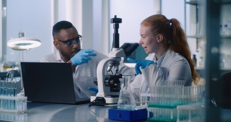 In advanced medical science laboratory, diverse team of two scientists working on creating new...