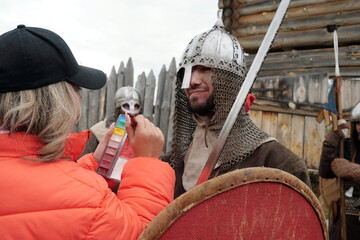 Event coordinator interacting with actors dressed in medieval armors and holding shields, preparing...
