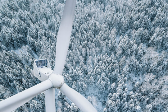 Wind turbine close-up. Aerial drone view of Wind turbine in winter landscape with snow covered trees woods. Alternative energy in winter.