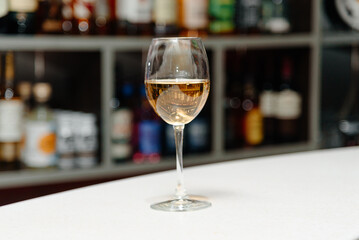 glass of wine on bar counter, shelves with alcohol bottles in background, nightlife concept
