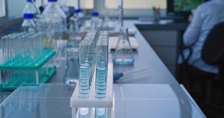 Medical science lab: Close up of chemist or scientist taking blue liquid with pipette from glass flask and pouring into test tubes for analysis. Advanced pharmacological laboratory. Scientific method.