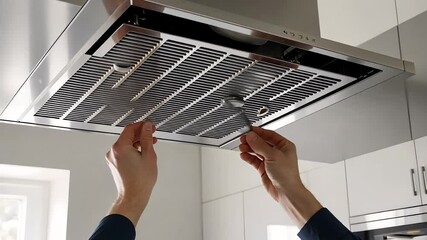 Person Replacing Filter in Kitchen Range Hood

