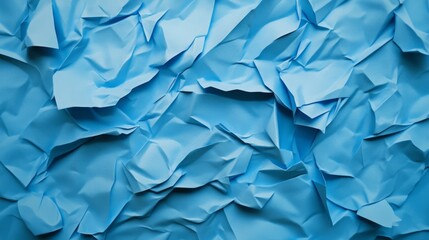 Obraz premium A textured surface of crumpled blue paper, showcasing various shades and folds, creating an abstract and dynamic visual effect.