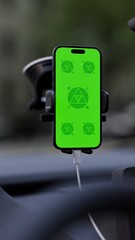 A phone with a green mockup screen is mounted on a car's dashboard. The setup suggests hands-free...