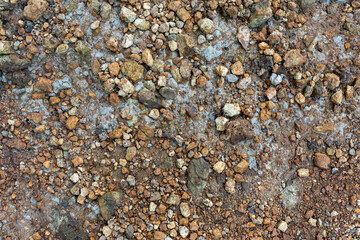 Abstract textured gray stone pebbles on a sandy beach with a pattern of small rocks and gravel
