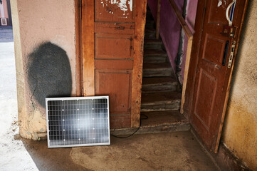 Photovoltaic solar panel at weathered, textured wall with peeling paint. Juxtaposition of modern...