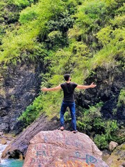 person on the rock between mountains and river 