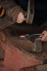 Skilled artisan working with traditional forging tools, heating metal over an anvil. Close-up shot showcasing hands and equipment, emphasizing detail and craftsmanship