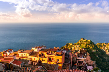 Fototapeta premium beautiful sunset scenic view of a coastline mountain town with nice roofs and streets with mountauns and hills and amazing cloudy sunset on background