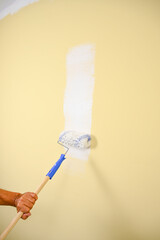 Vertical image of a paintbrush painting wall in yellow