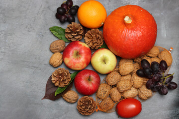 Autumn composition with pumpkins, apples and nuts on grey background