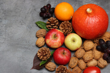 Autumn composition with pumpkins, apples and nuts on grey background