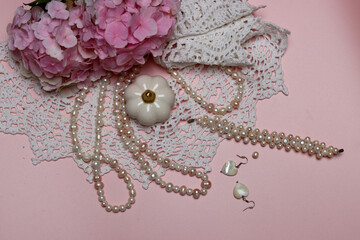 White lace, pearls and pink hydrangea on pink background with space for text