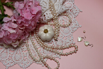 White lace, pearls and pink hydrangea on pink background with space for text