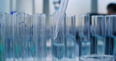 Medical science lab: Chemist or scientist pours blue liquid into test tubes for research using pipette. Vaccine development. Advanced pharmacological laboratory. Scientific method. Macro Close Up.