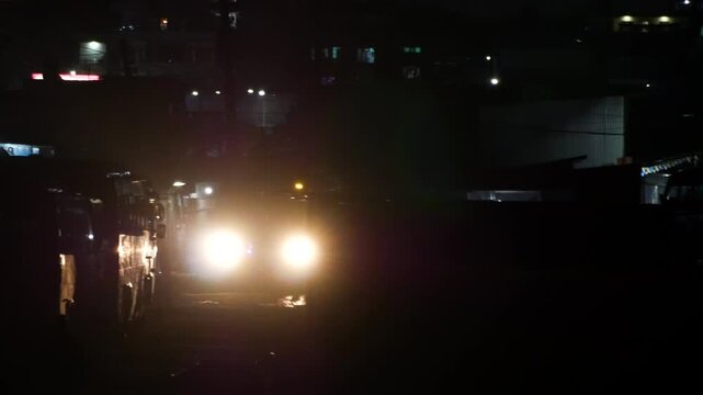 Bus with headlights flashing and driving at night emitting lens flare.