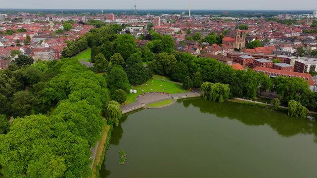 Aerial view of the promenade and Aasee Lake in Munster, germany. Lush green trees line the waterfront with the cityscape in the background