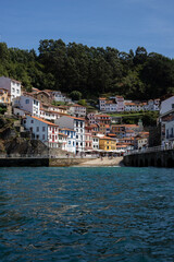 A picturesque coastal village nestled on a hillside, with colorful houses cascading down to the waterfront. The crystal-clear water reflects the vibrant buildings, creating a stunning scene.

