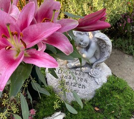 Kleine Engel mit Herz und Blumen auf dem Friedhof im Herbst