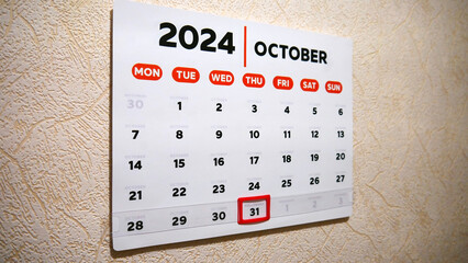 A wall calendar October page with a red frame cursor on Halloween date