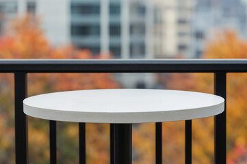 Empty round white table on a balcony overlooking autumn trees
