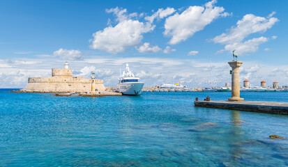 Scenic view of Mandraki Harbour in Rhodes, Greece, featuring Saint Nicholas Fortress and the site of the Colossus of Rhodes.