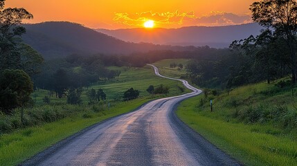 Fototapeta premium Road leading through lush green hills at sunset