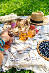 Wine in hands of woman at picnic. Selective focus.